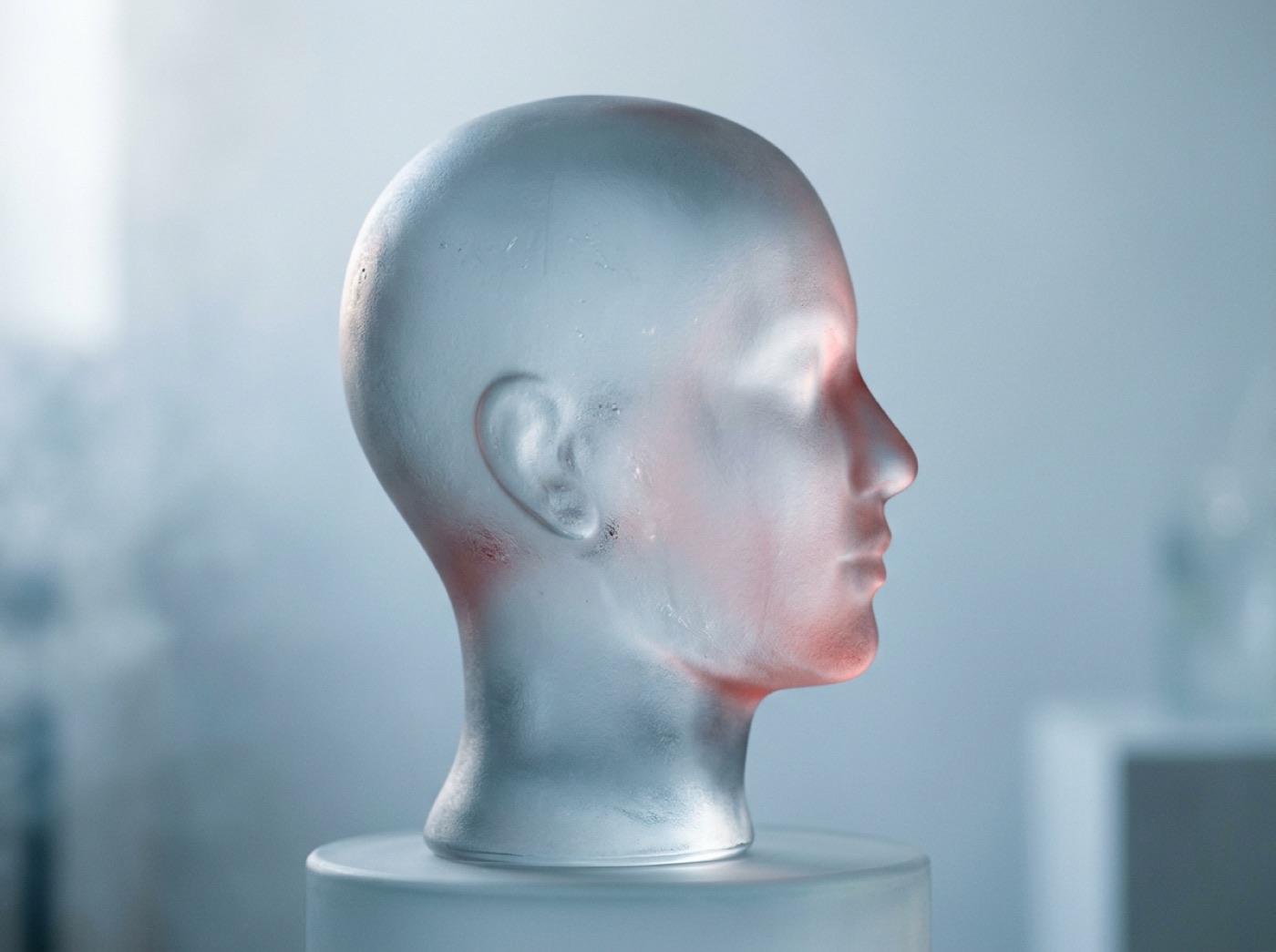 A glass head in soft morning light with a faint, fading glow on one side